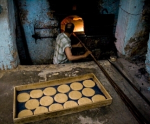 baker reaches into oven with peel